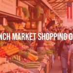 A bustling French market scene with colorful fresh produce, cheeses, and bread on display, vendors in aprons, lively crowd, warm sunlight, rustic ambiance, realistic.